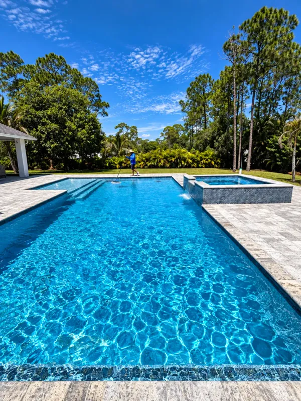 Crystal-clear rectangular pool and raised spa with a sheer-descent waterfall in a West Palm Beach backyard